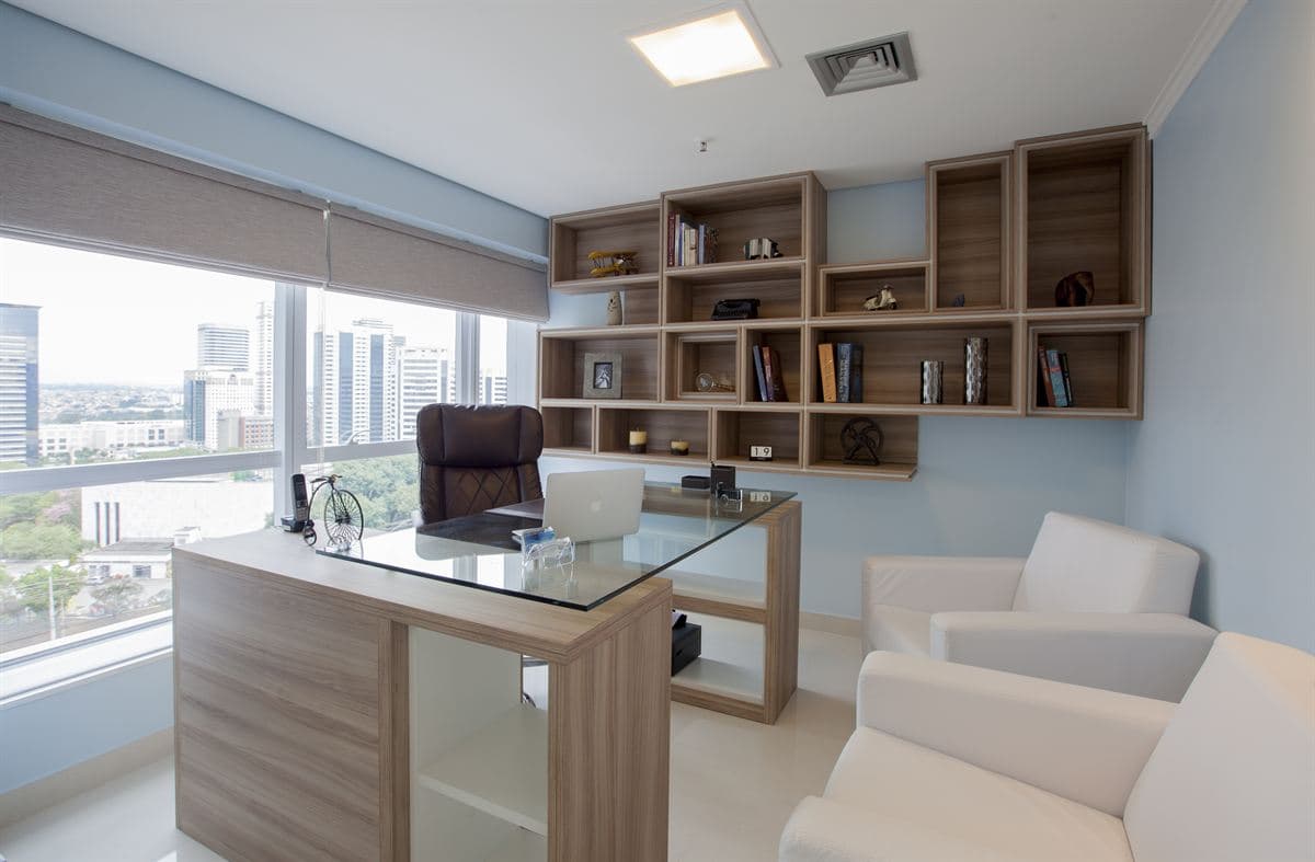 Sala de consulta com mesa, poltronas e vista para a cidade